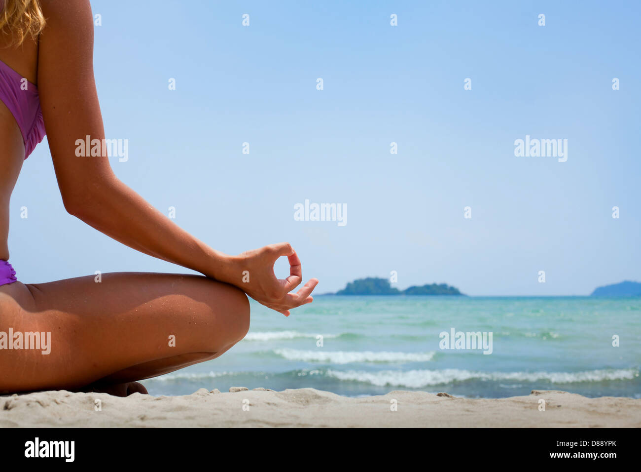 yoga background, woman in lotus position meditating on the beach Stock Photo