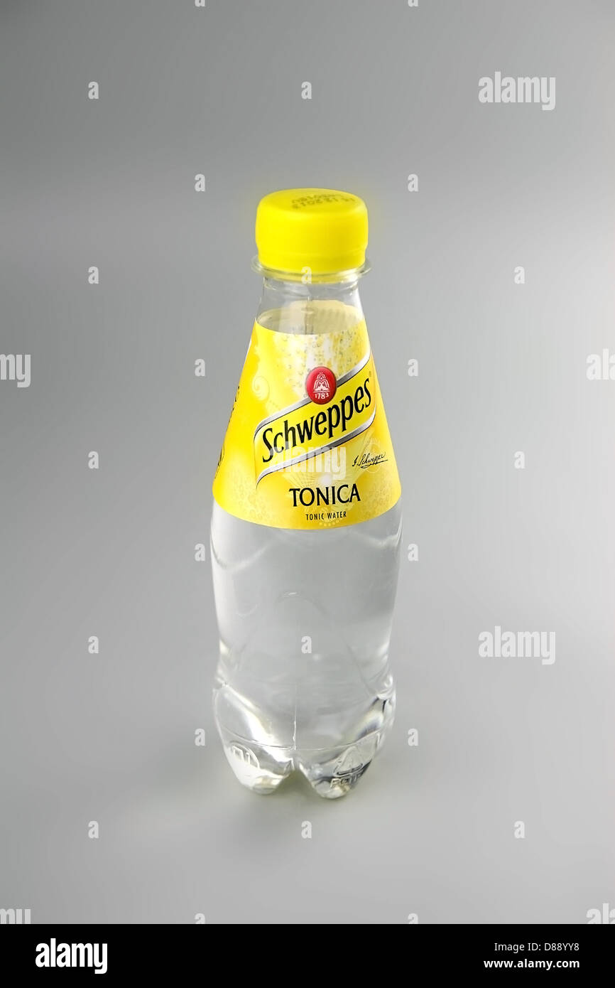 Small branded Schweppes transparent tonic water bottle in plain normal light on a grey background. Stock Photo