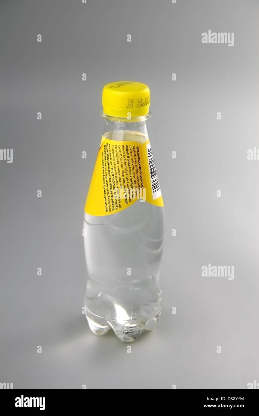 Small unbranded transparent tonic water bottle in plain normal light on a grey background. Stock Photo