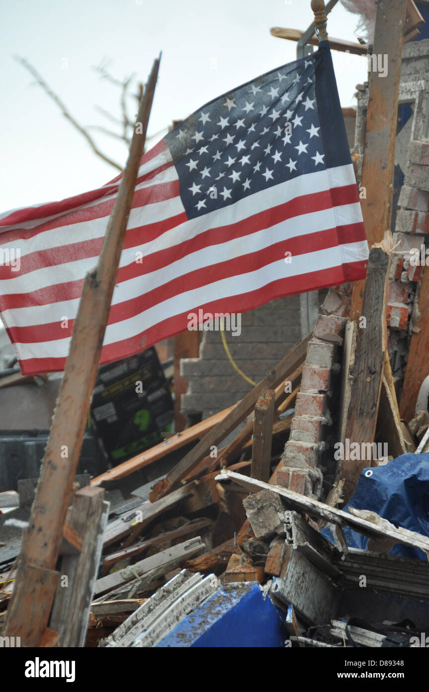 An American flag flies over the rubble of a home destroyed by an EF-5 tornado May 21, 2013 in Moore, Oklahoma. The massive storm with winds exceeding 200 miles per hour tore through the Oklahoma City suburb May 20, 2013, killing at least 24 people, injuring more than 230 and displacing thousands. Stock Photo