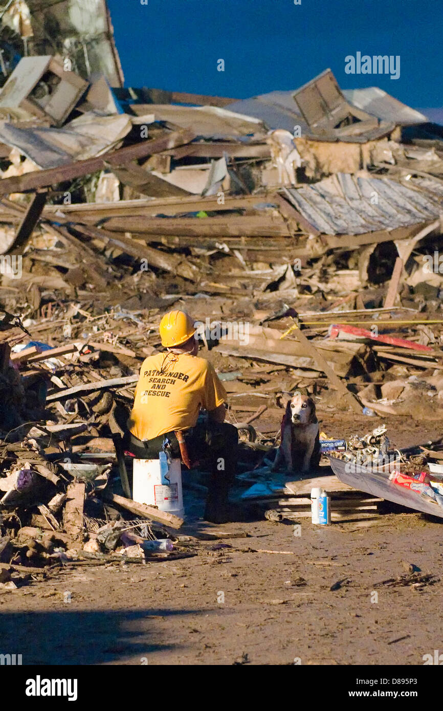 A rescue worker and his search dog rest during search operations in the aftermath of an EF-5 tornado that destroyed the town May 20, 2013 in Moore, Oklahoma. The massive storm with winds exceeding 200 miles per hour tore through the Oklahoma City suburb May 20, 2013, killing at least 24 people, injuring more than 230 and displacing thousands. Stock Photo