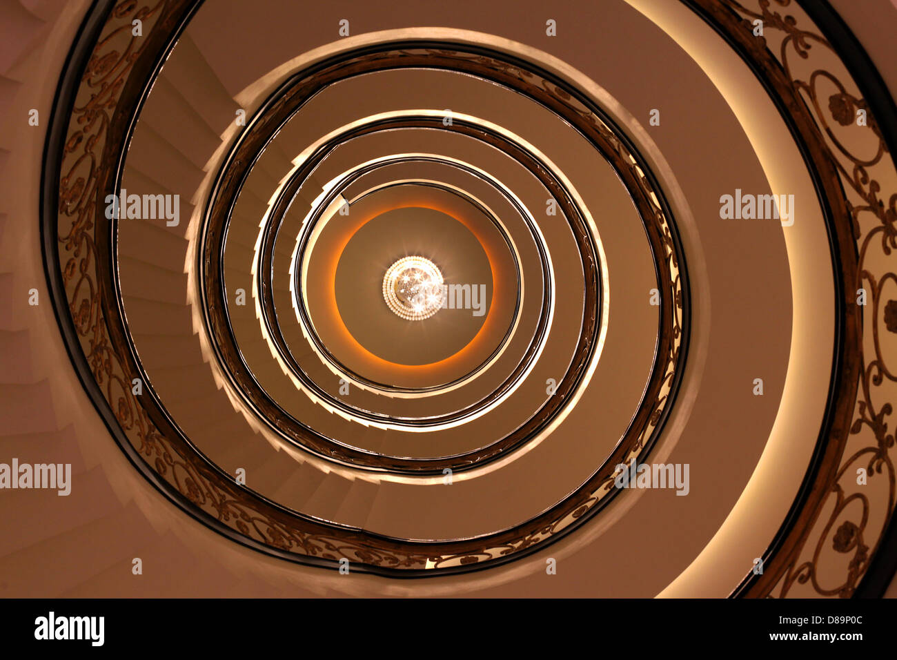 A staircase with a beautiful spiral staircase in the Hotel Godwin in New Delhi. The golden-designed staircase was renovated and comprises a total of four floors. At the end of the stairs you can see a chandelier. Stock Photo