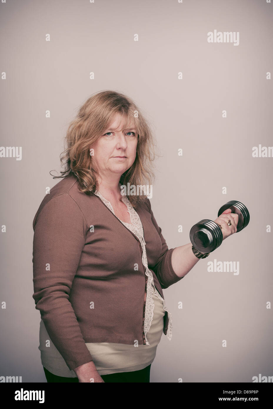 Middle-aged Caucasian woman lifts dumbbell. Stock Photo