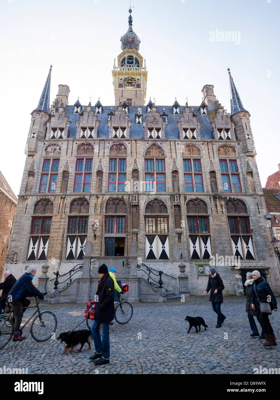 Passersby with dogs walk in front of the old Veere townhall. Stock Photo