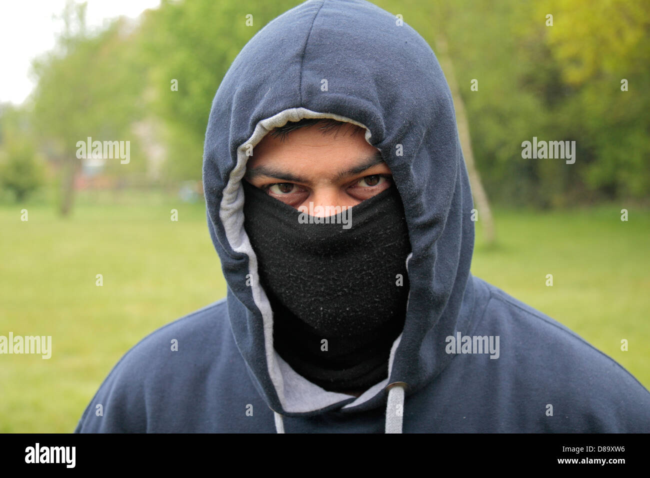 A British Asian man wearing a hoddie with his face covered. Stock Photo