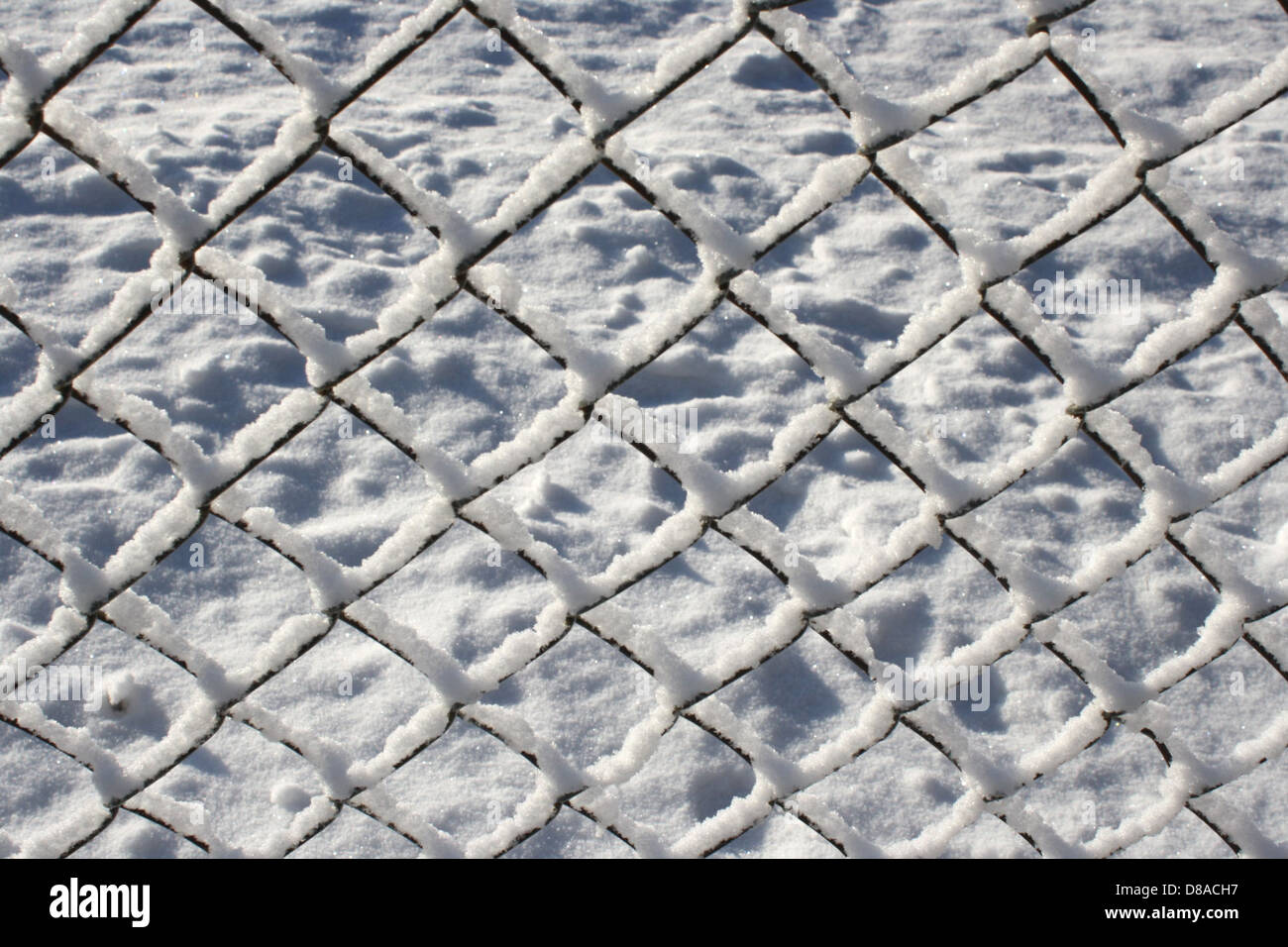 A chain-link fence covered with a layer of snow, creating a winter ...