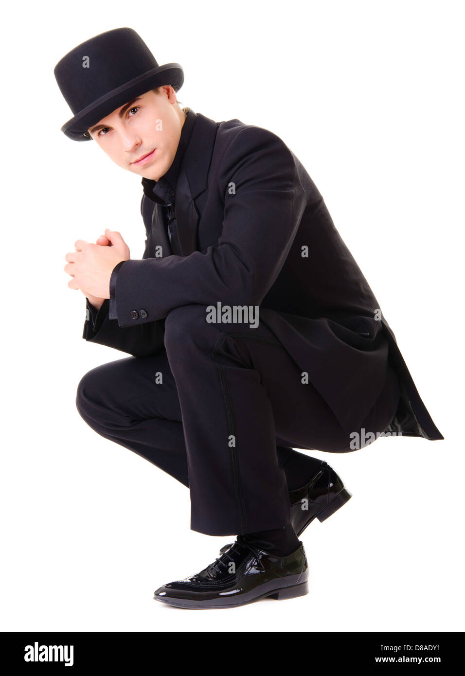 Young attractive man in black suit and hat isolated on white background ...