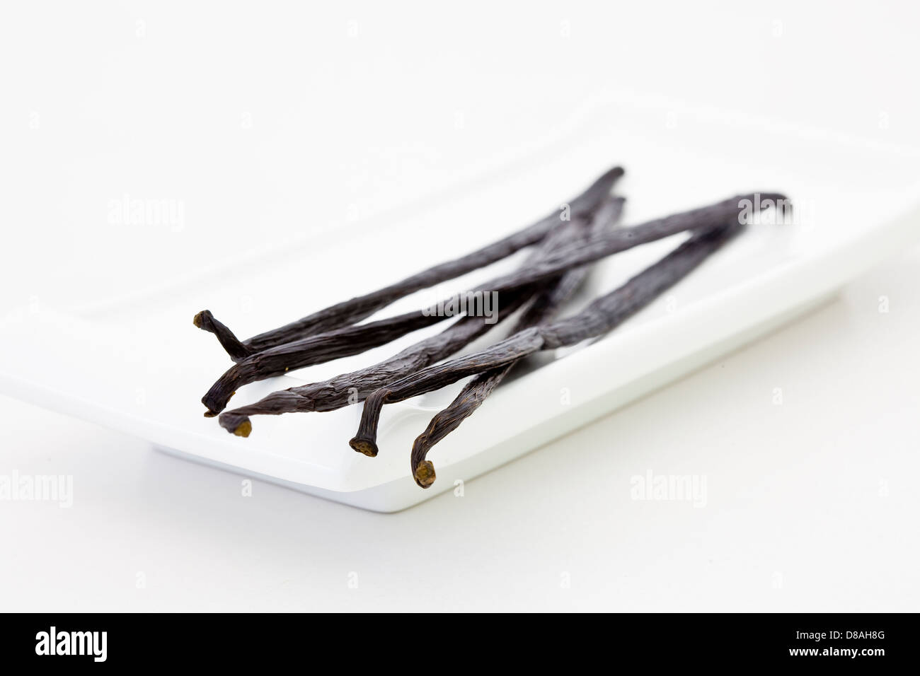 Five vanilla bean pods on a white dish Stock Photo Alamy