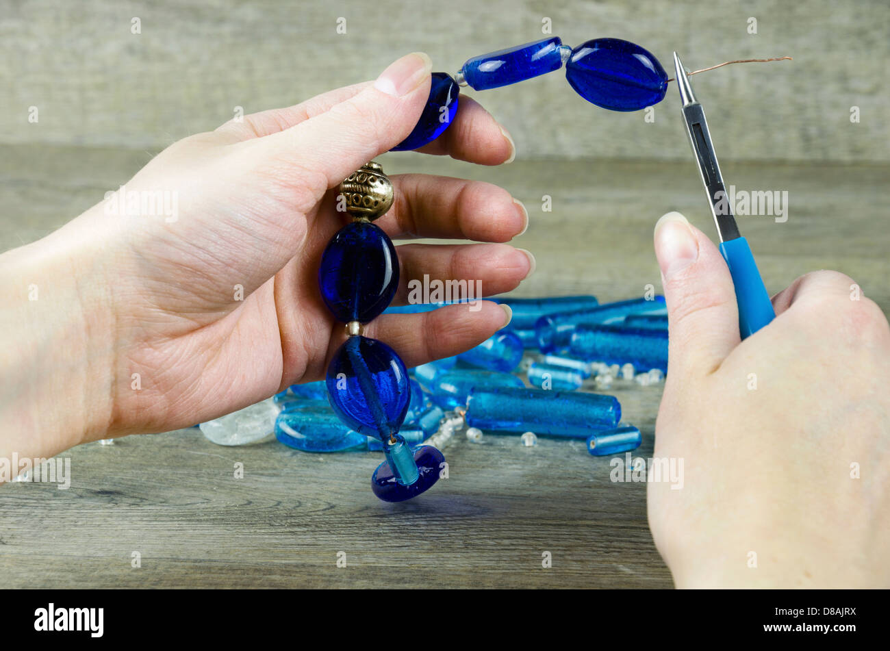 Woman's hands making a necklace from glass beads Stock Photo
