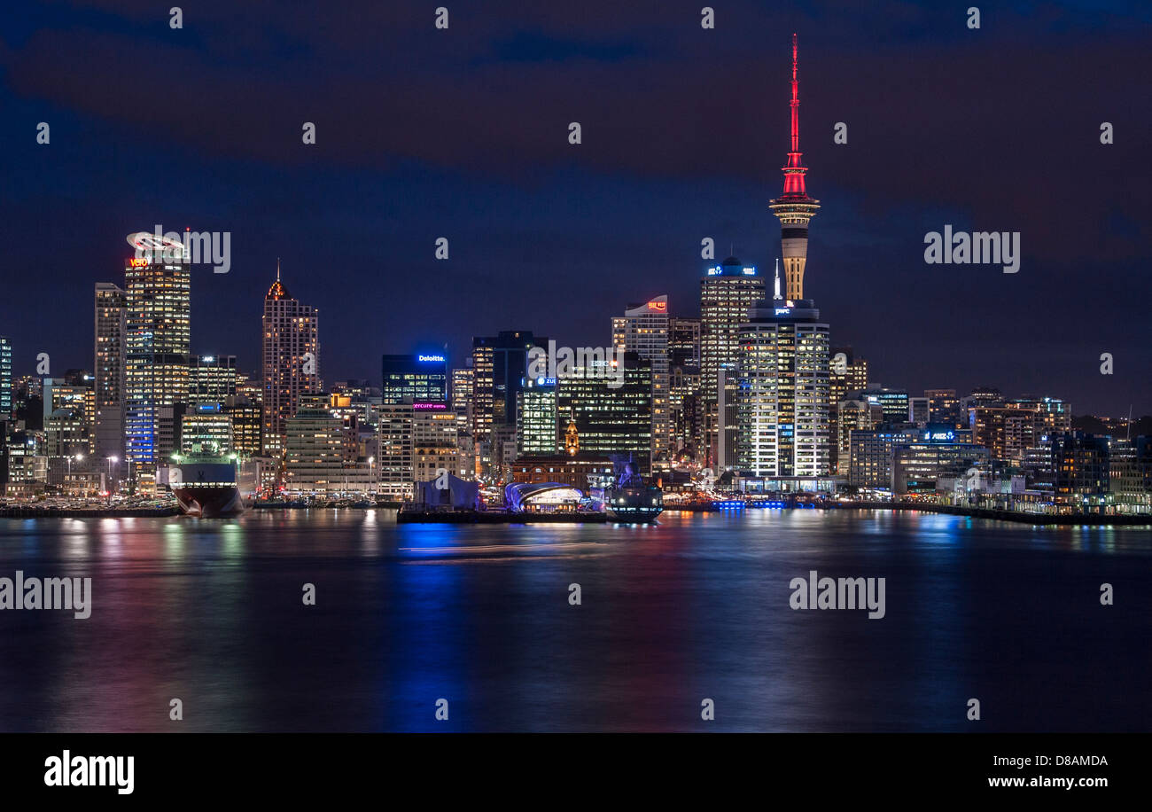 The lights of downtown Auckland, CBD and Sky Tower reflect across the harbour at night. Stock Photo