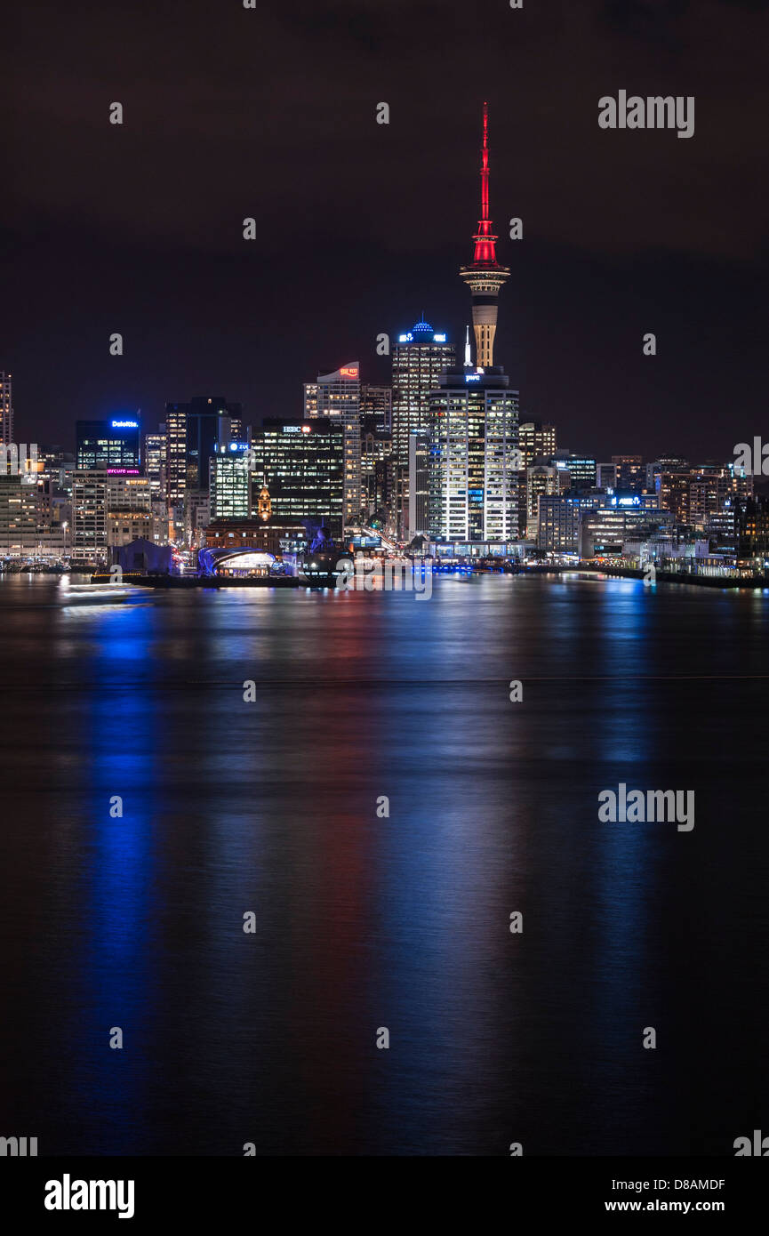 The lights of downtown Auckland, CBD and Sky Tower reflect across the harbour at night. New Zealand Stock Photo