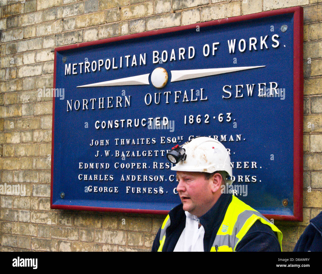 A worker in front of the name plate for the Northern Outfall Sewer at
