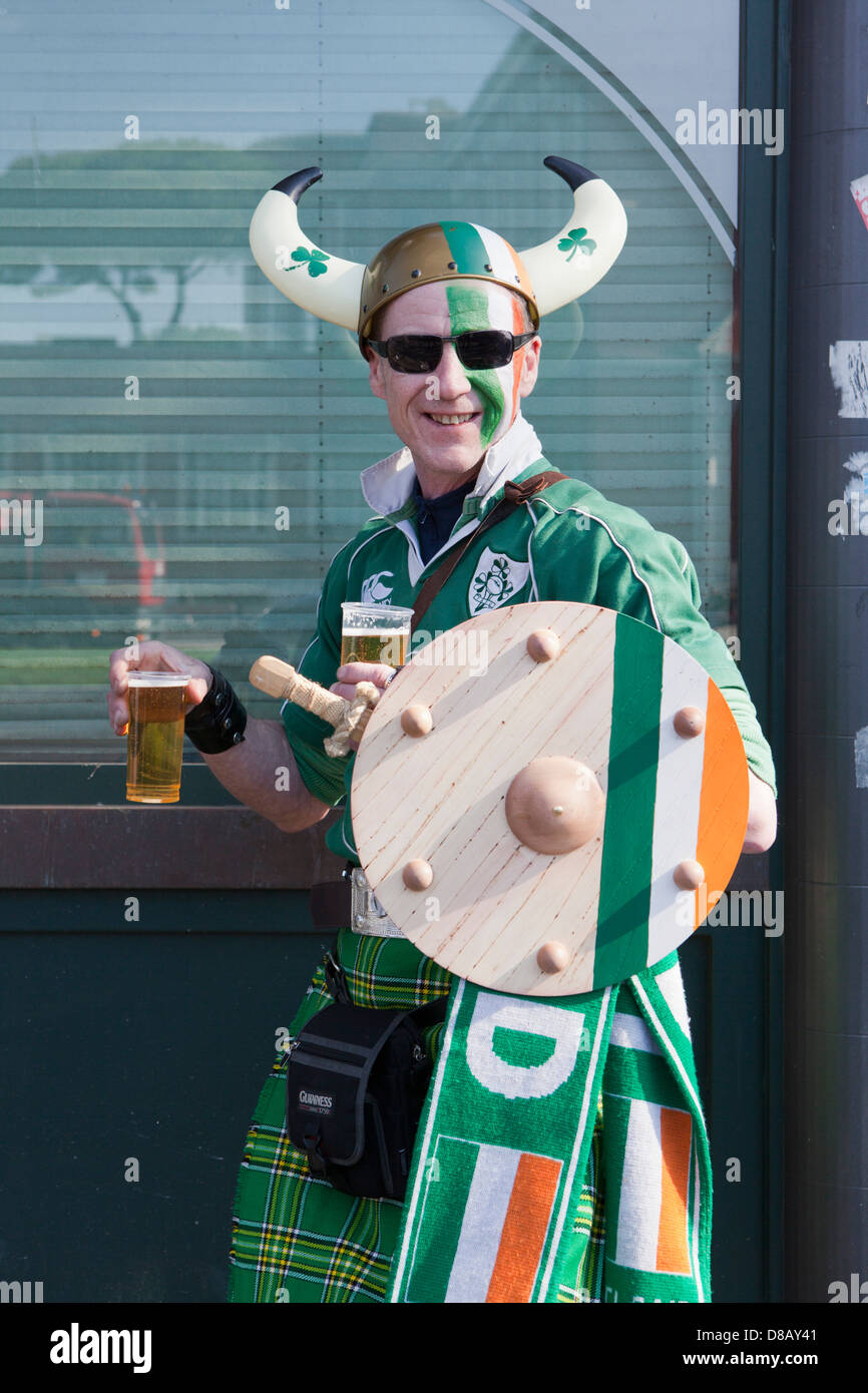 Ireland rugby supporter in Rome wearing kilt and and Irish shirt and horned helmet carrying a sword and shield with two beers Stock Photo
