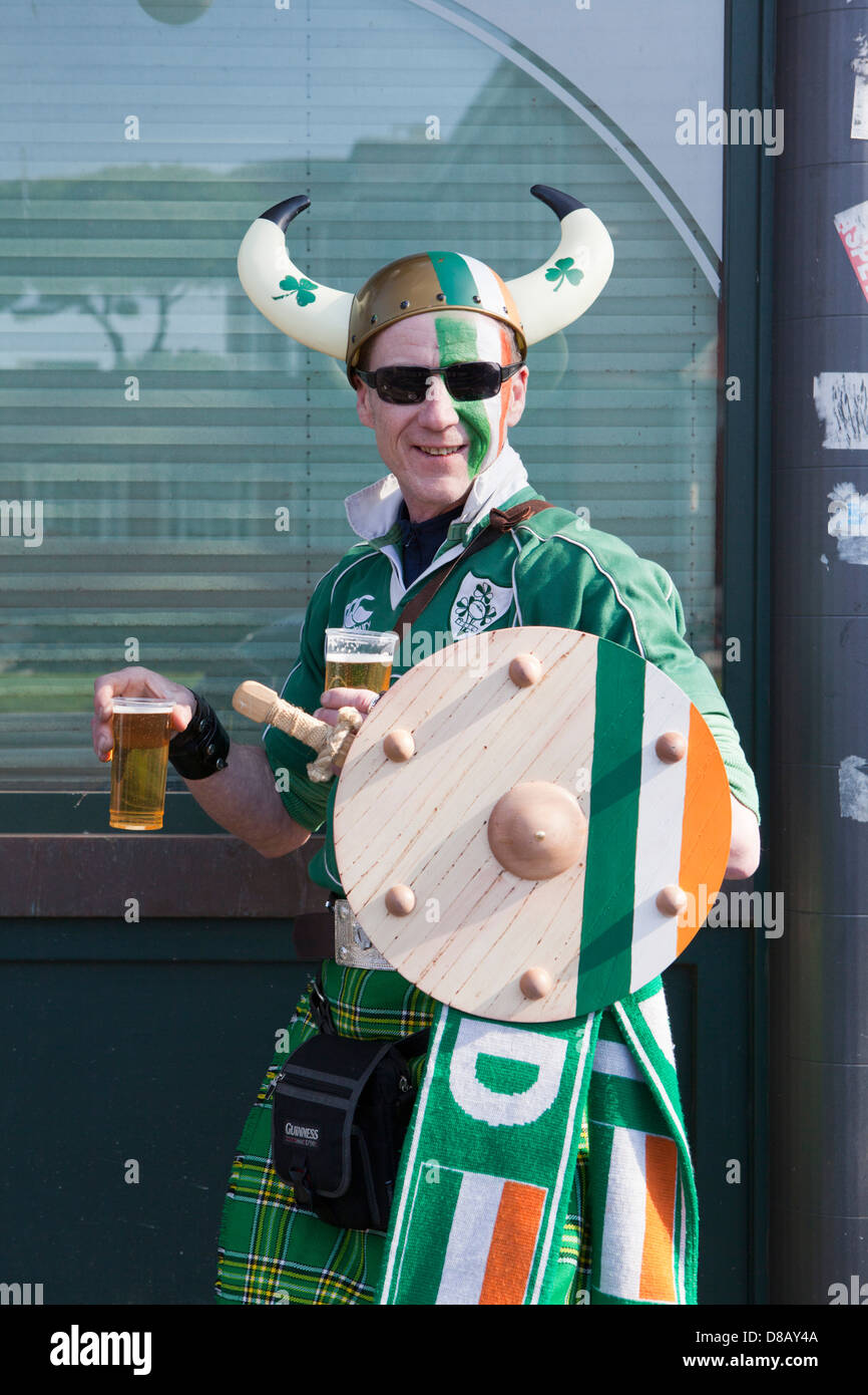 Ireland rugby supporter in Rome wearing kilt and and Irish shirt and horned helmet carrying a sword and shield with two beers Stock Photo