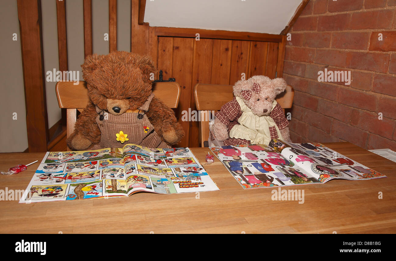 Teddy bears reading comics at table Stock Photo