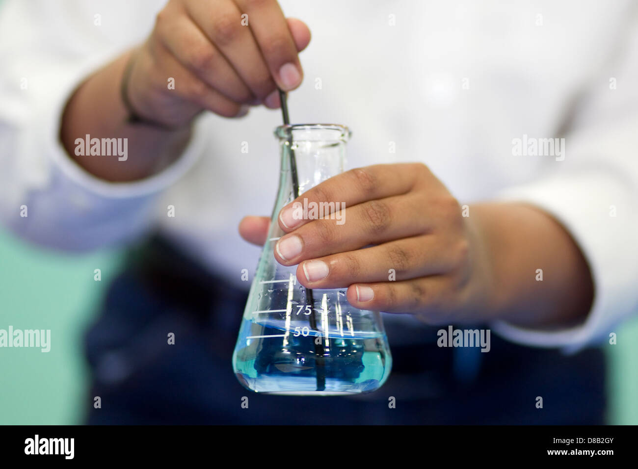 Male high school student of middle eastern decent, uses beaker  during science fair demonstration Stock Photo