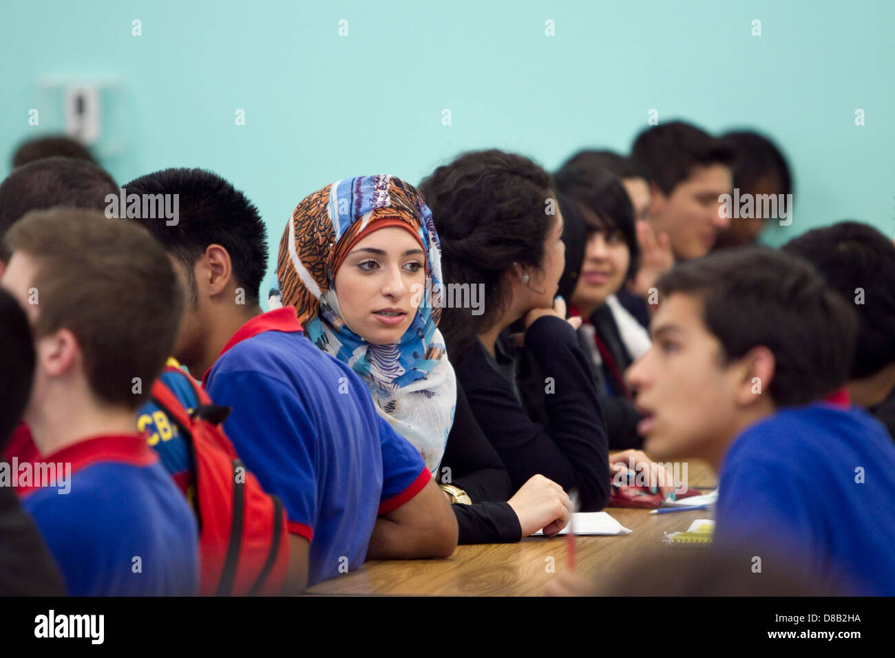 Multi-ethnic groups of high school students including females wearing hijab during school assembly in cafeteria of Austin, Texas Stock Photo