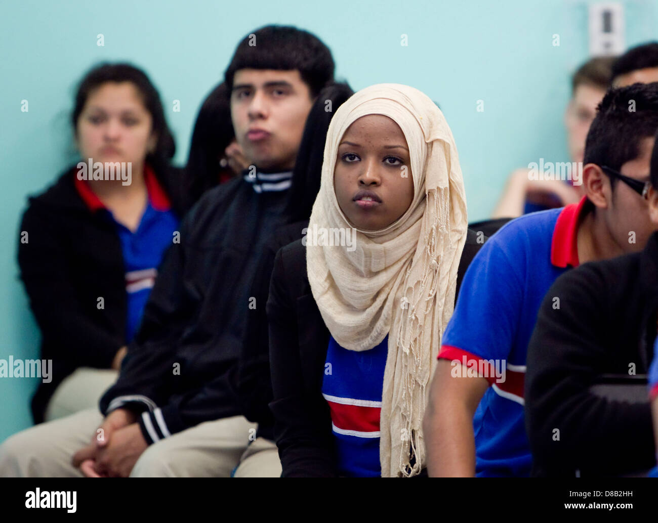 Multi-ethnic groups of high school students including females wearing hijab during school assembly in cafeteria of Austin, Texas Stock Photo