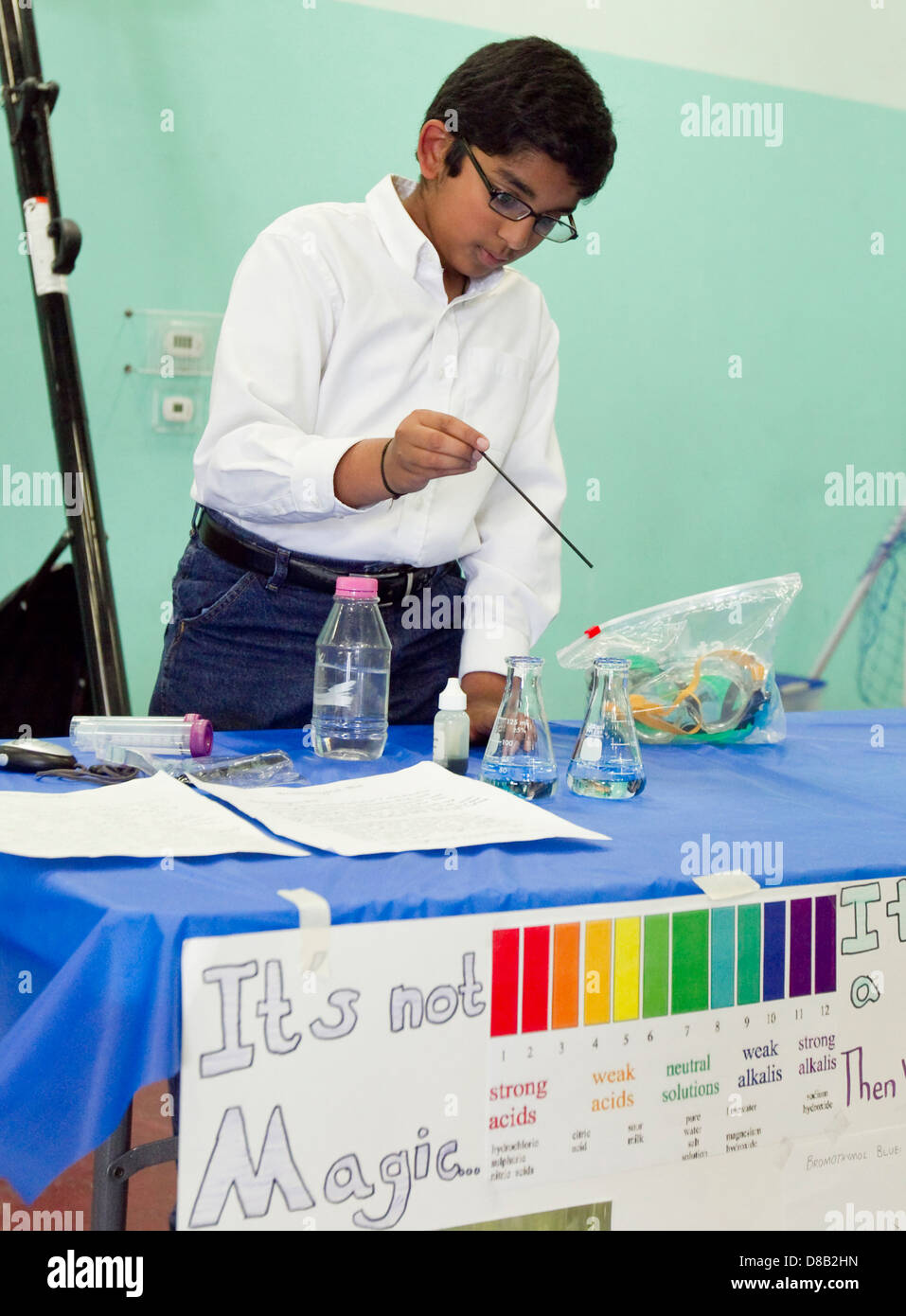 Male high school student of middle eastern decent, uses beaker  during science fair demonstration Stock Photo