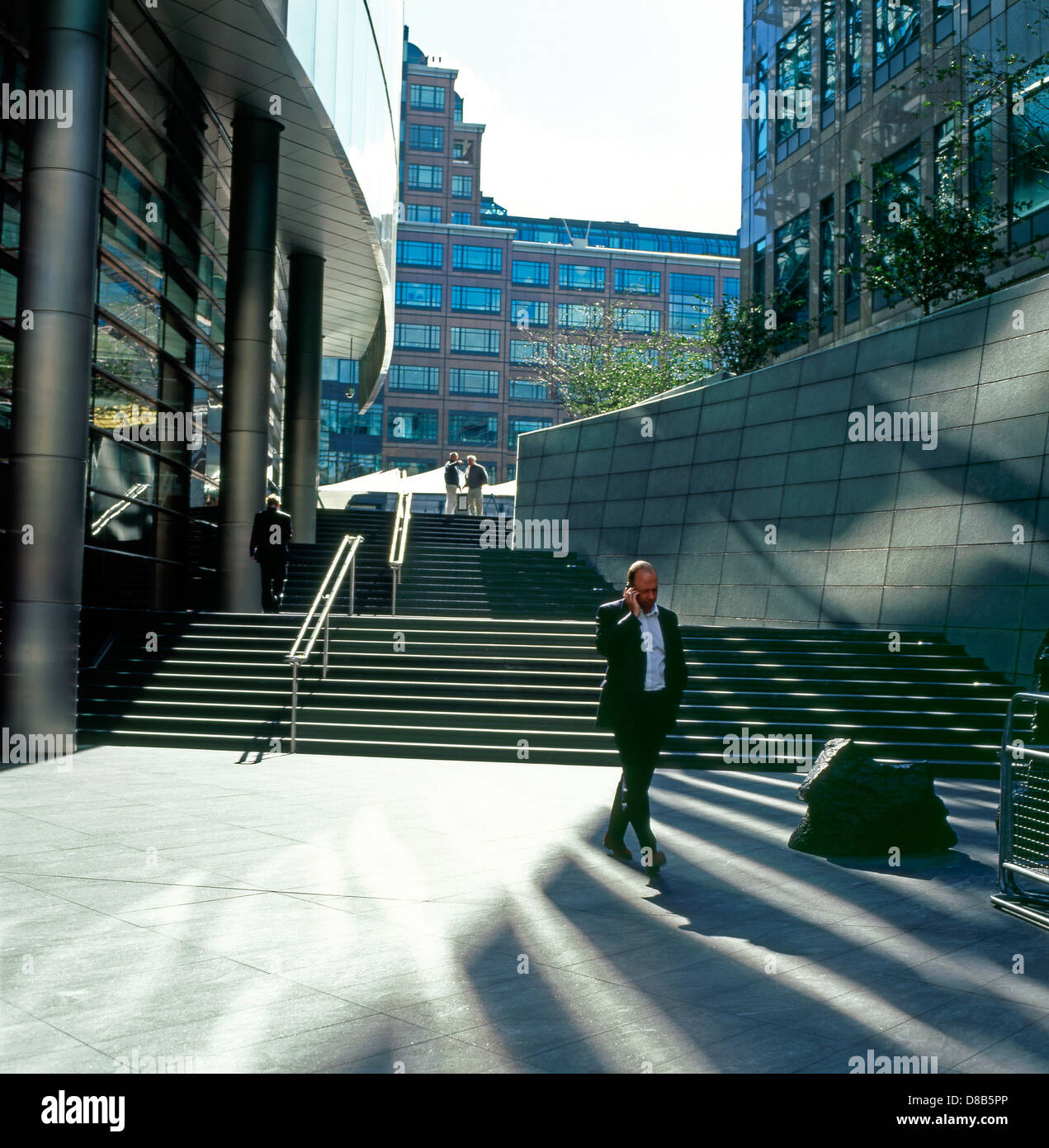 Businessman talking on mobile phone at noon by the steps leading to Broadgate near Liverpool Street Station UK  KATHY DEWITT Stock Photo