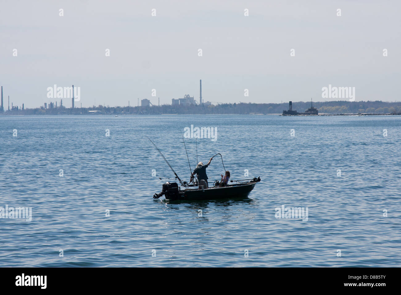 small boat man fishing blue water lake Stock Photo