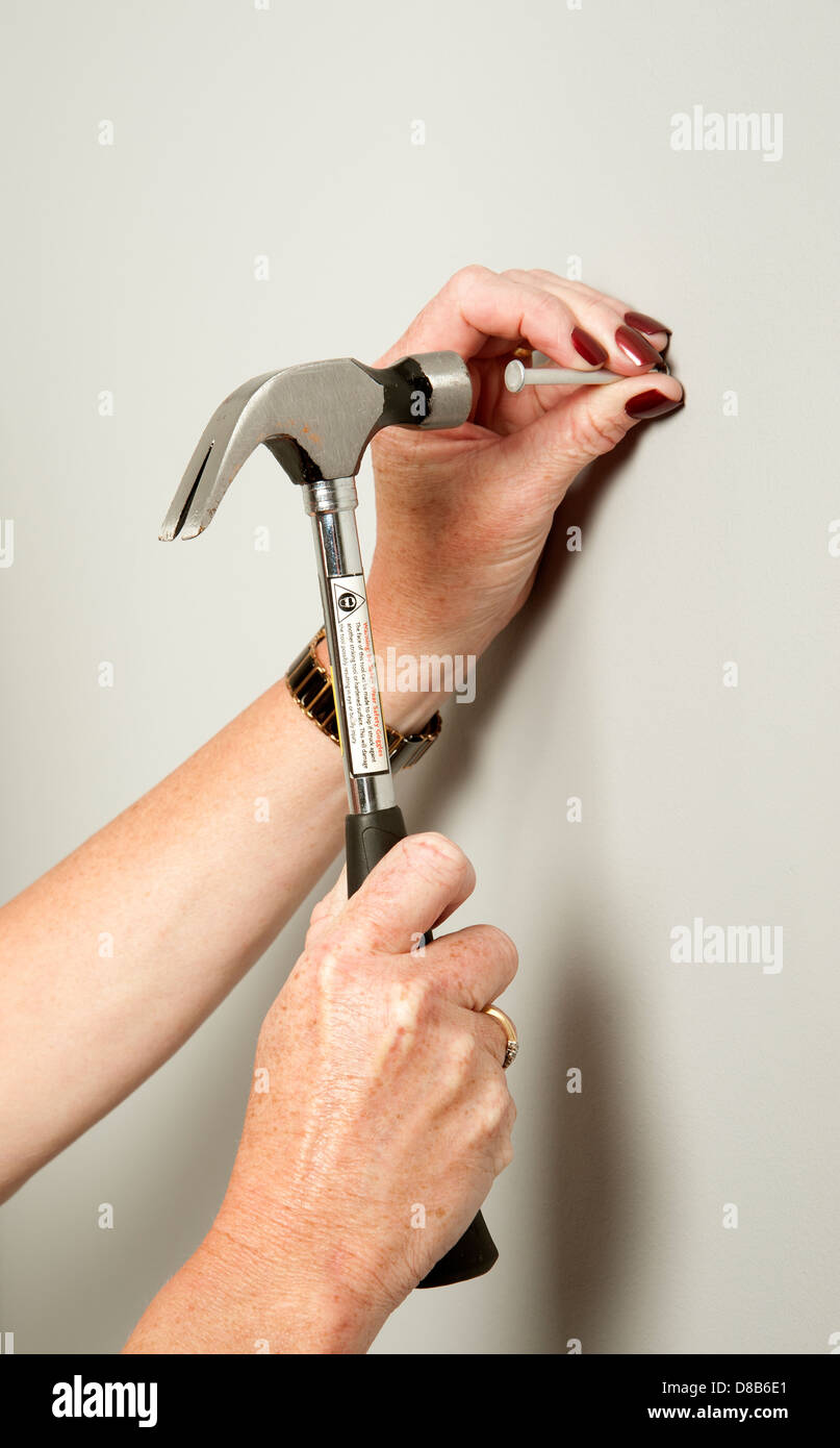 Woman using a hammer to bang a nail into a wall Stock Photo - Alamy Woman using a hammer to bang a nail into a wall Stock Photo - Alamy
