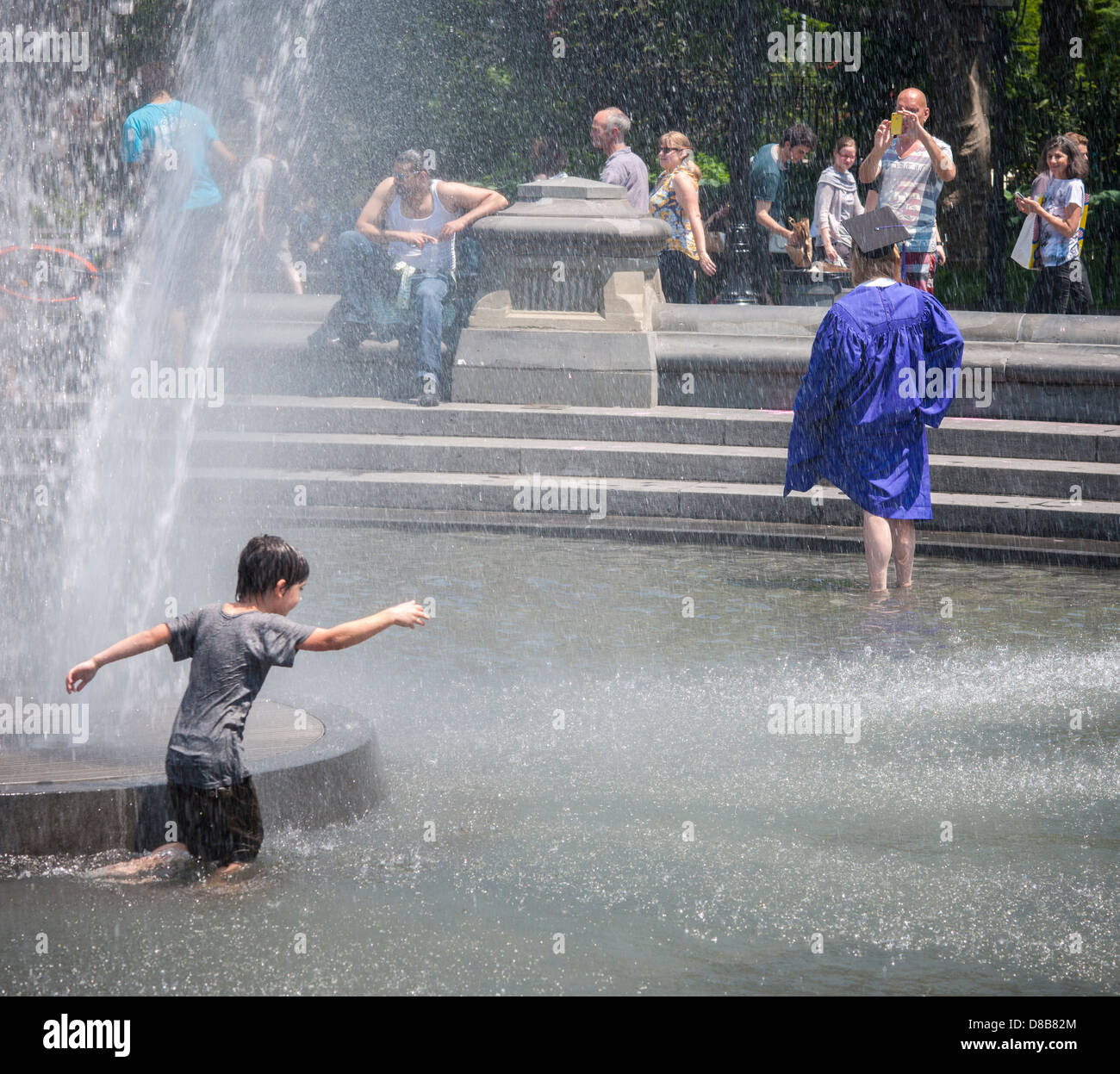 An NYU graduate in her cap and gown poses in the fountain in Washington