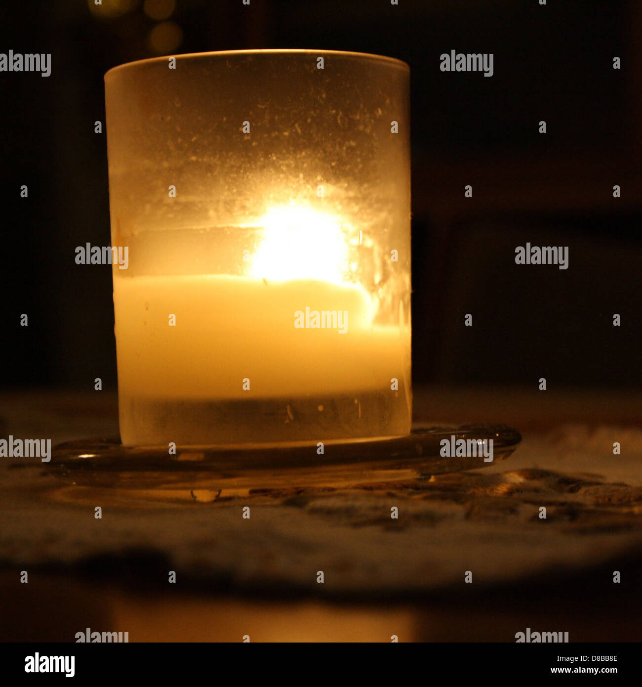 A candle is placed in a glass holder, casting a soft glow. The image ...
