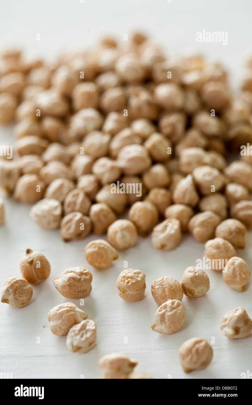 Closeup of a pile of uncooked chickpeas on a white table surface. Stock Photo