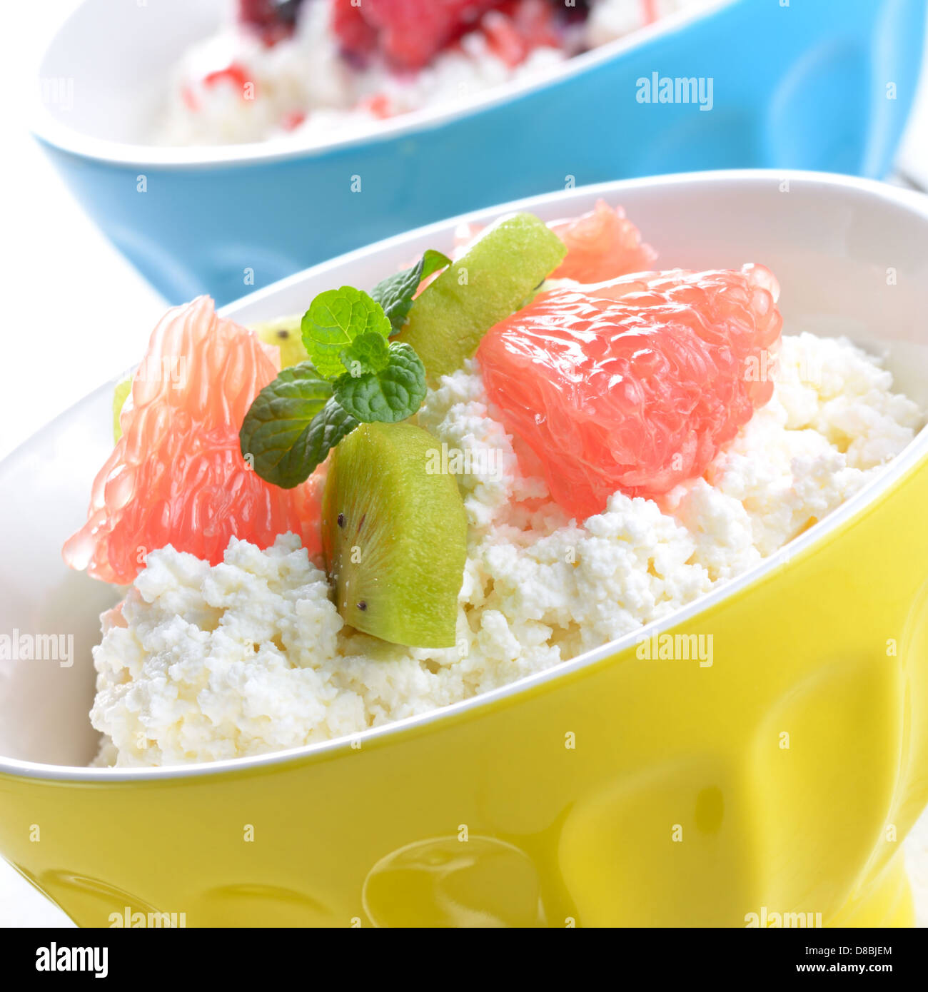 Cottage cheese in yellow bowl with kiwi, grapefruit and mint Stock