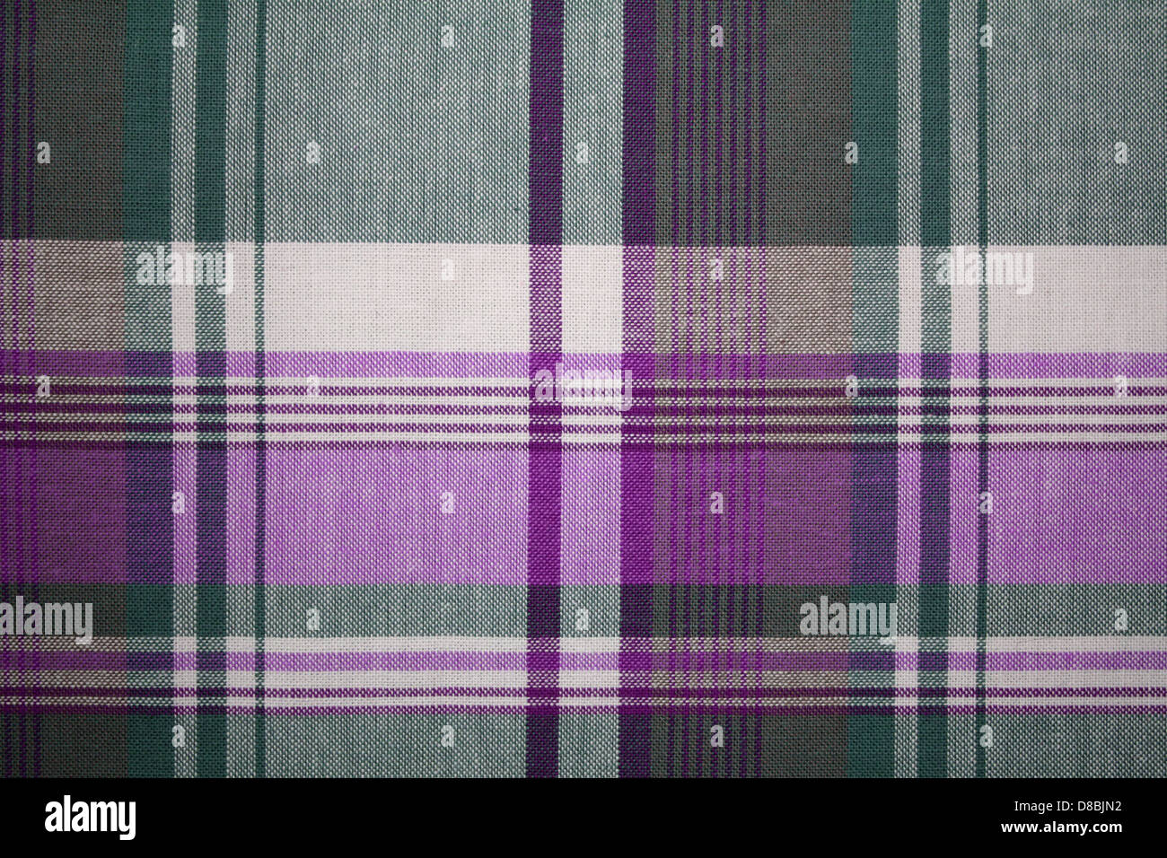 A close-up of a plaid fabric with a pattern in purple and green shades ...