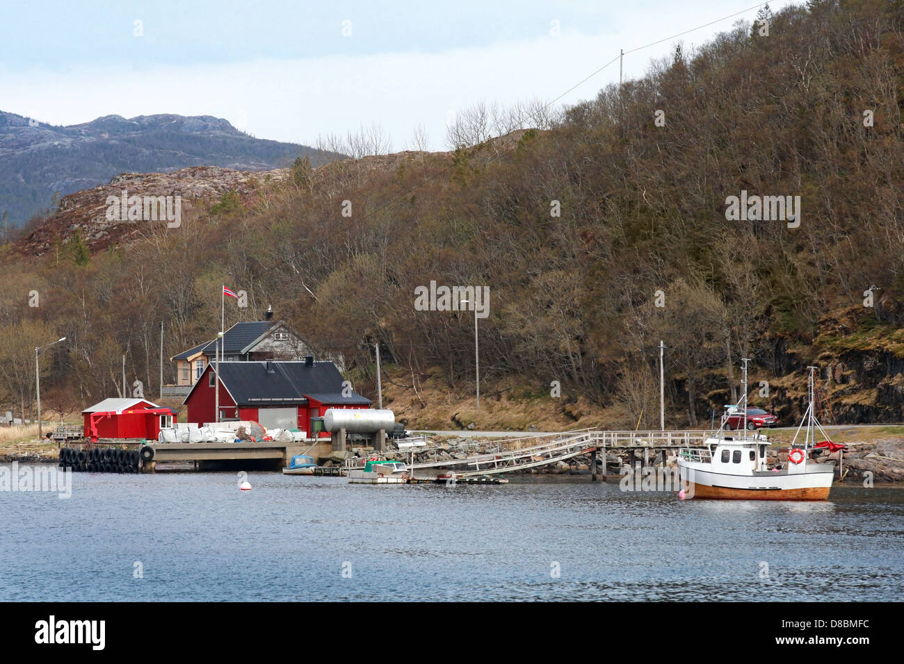Traditional small Norwegian village with red wooden houses and small fishing boat nearby Stock Photo