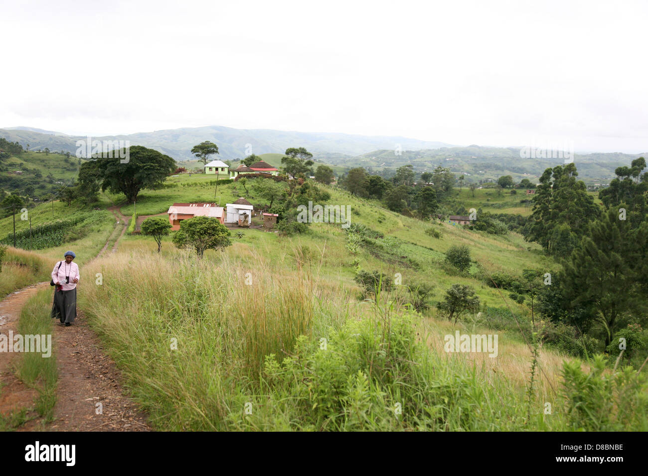 elderly woman walks up path away from house Stock Photo