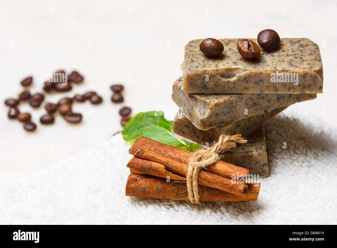 Stack of handmade flavored soap bars with coffee beans, cinnamon and lavender leaf on white towel. Stock Photo