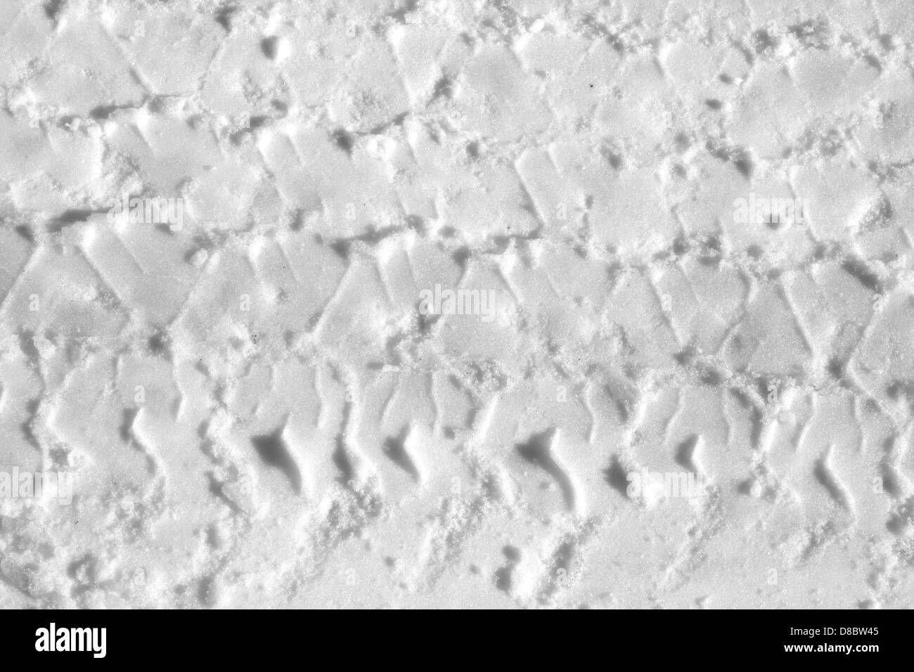 A close-up of tire tracks in the snow, showing the detailed texture ...