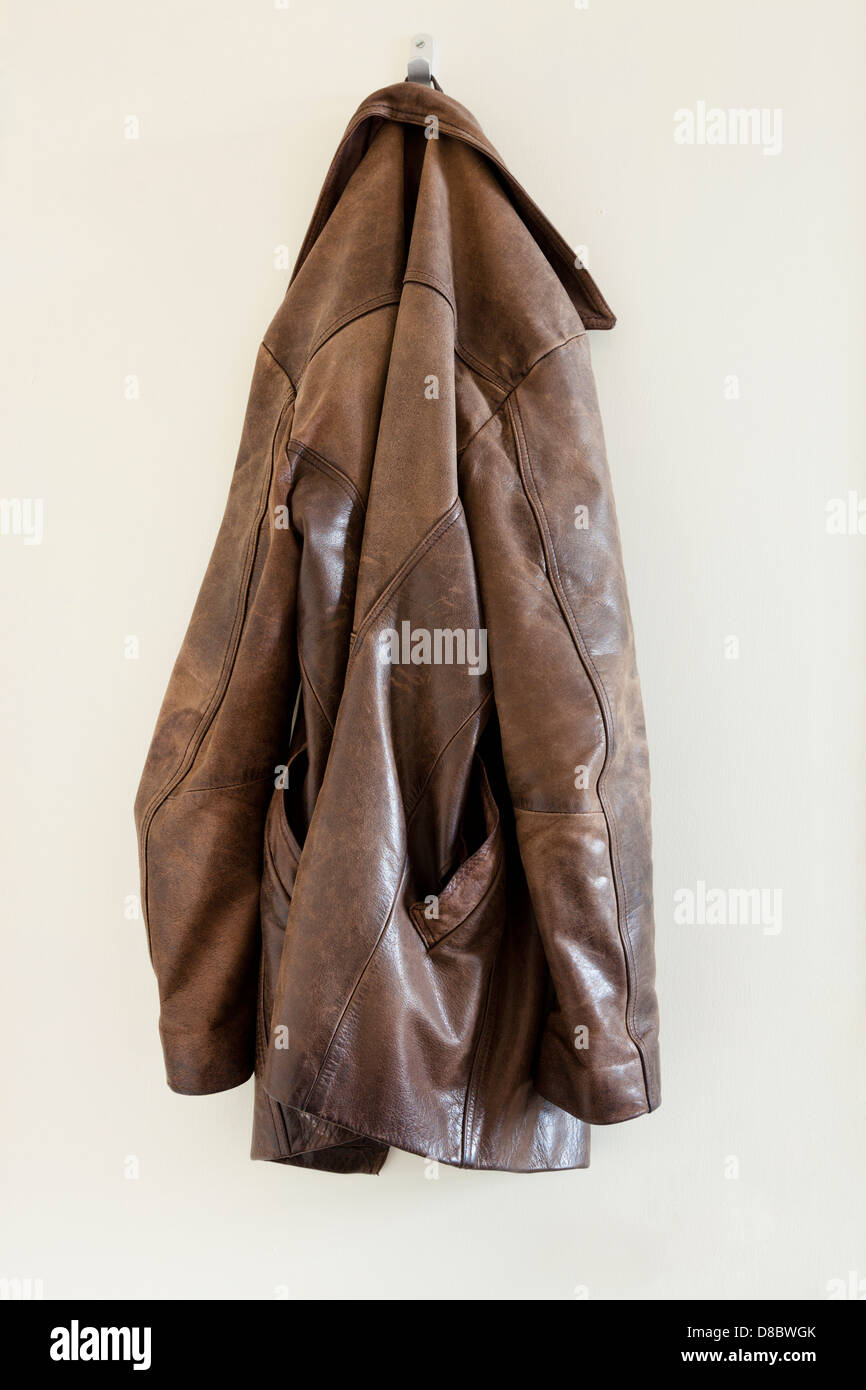 Old brown leather jacket hanging on the back of a door Stock Photo