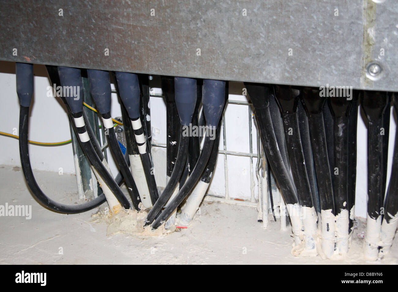 Electrical cables emerging from firestopping in services duct Stock Photo