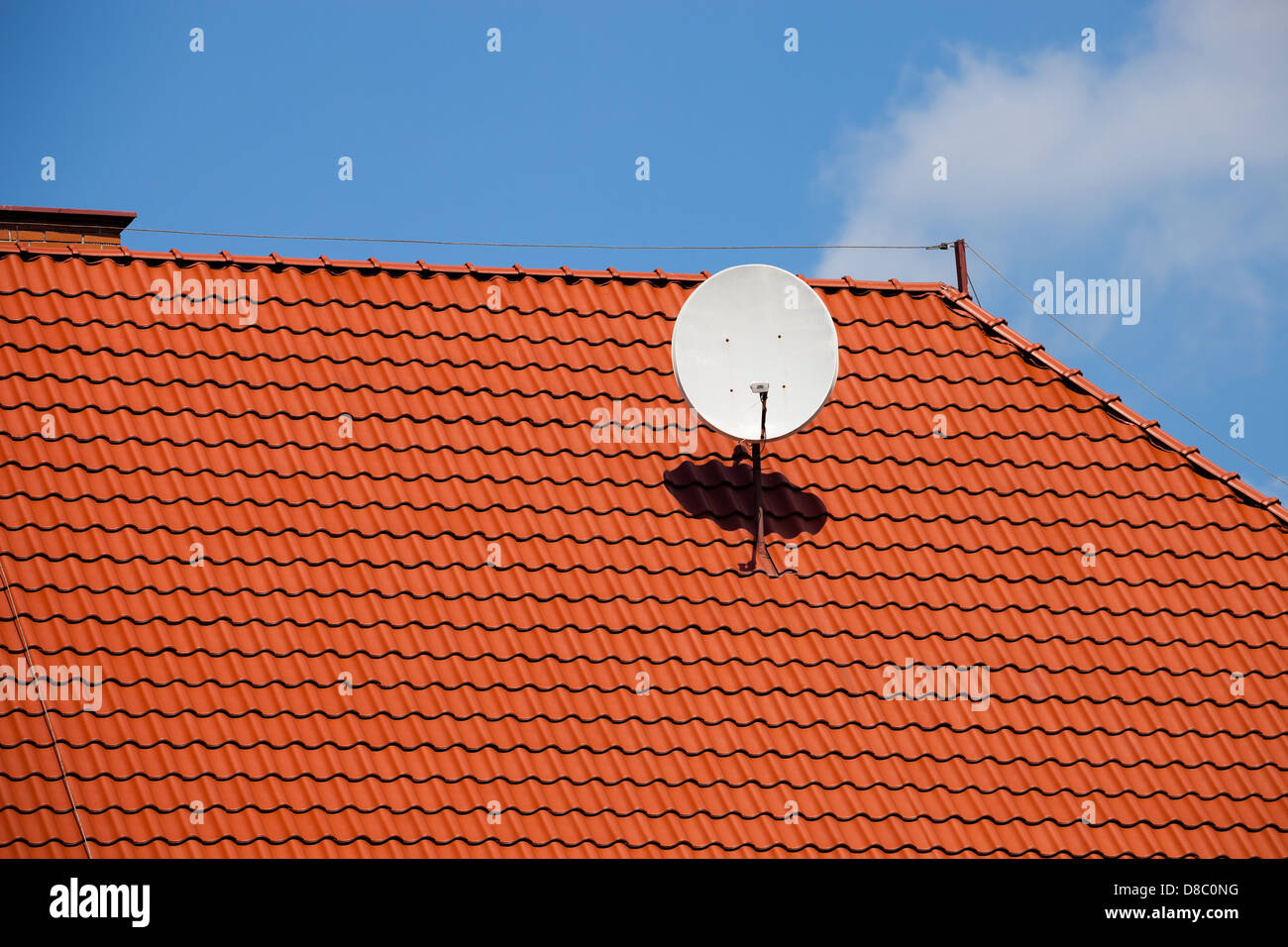 Tv satellite dish on red tiles roof. Stock Photo