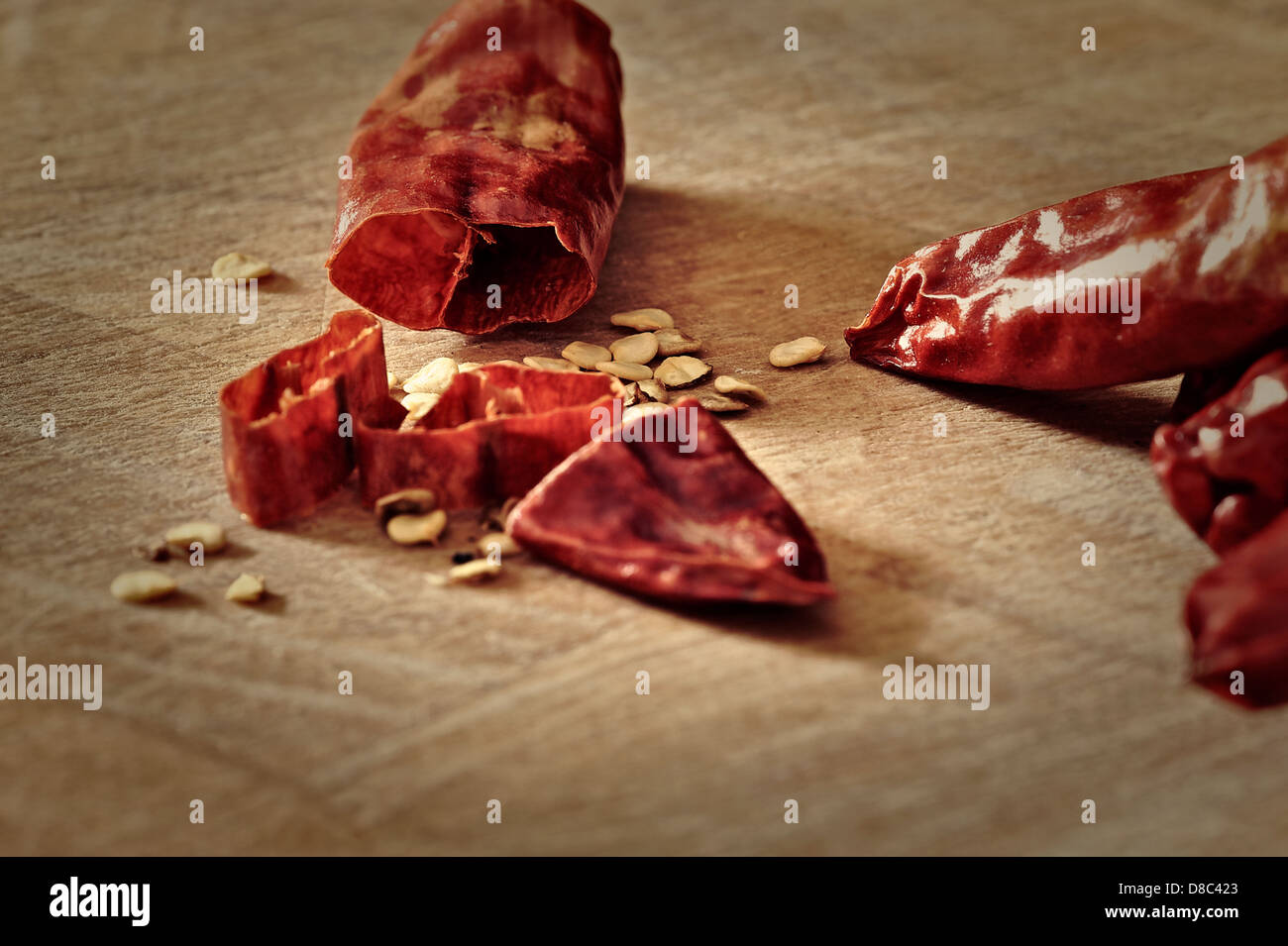 Sliced, dried, serrano (Sport) chilli pods and seeds on a chopping board. Capsaicin, an analgesic, is derived from chillies. Stock Photo