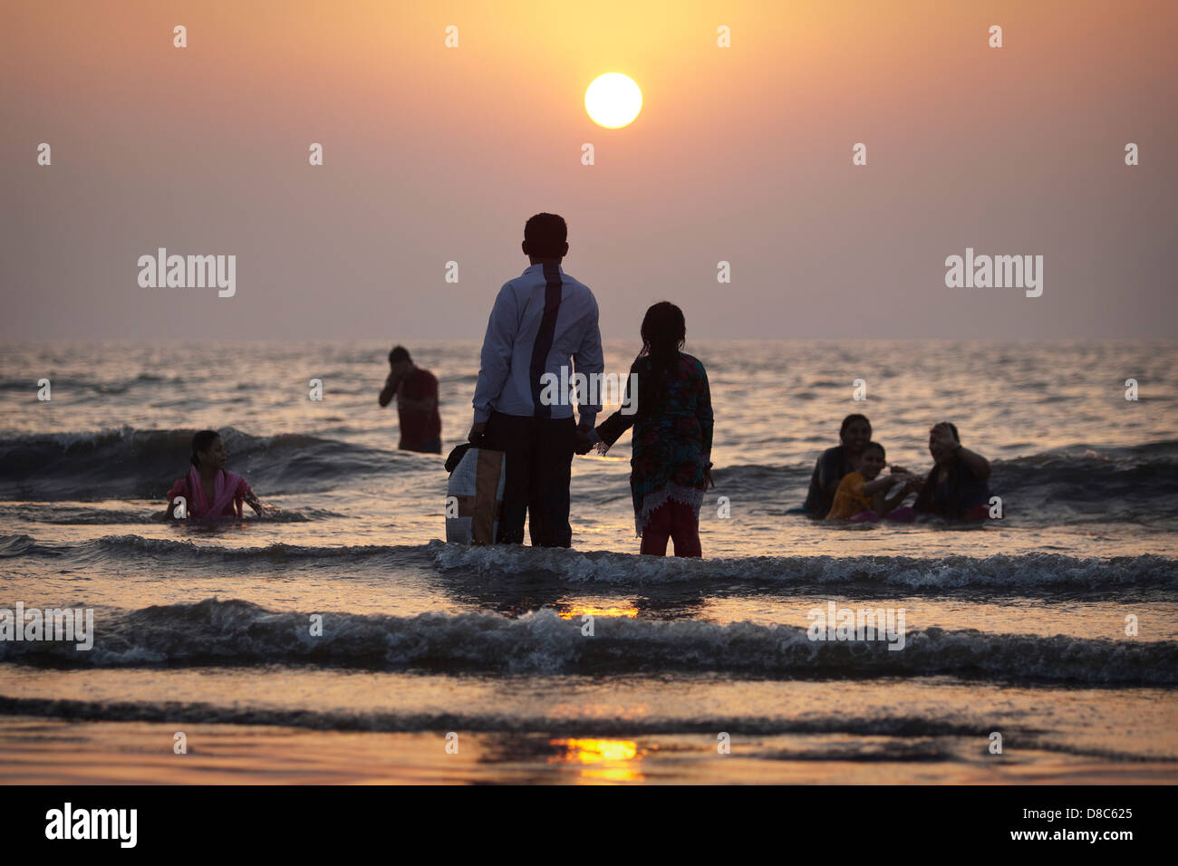 People watching the setting sun on a beach in Mumbai, India Stock Photo