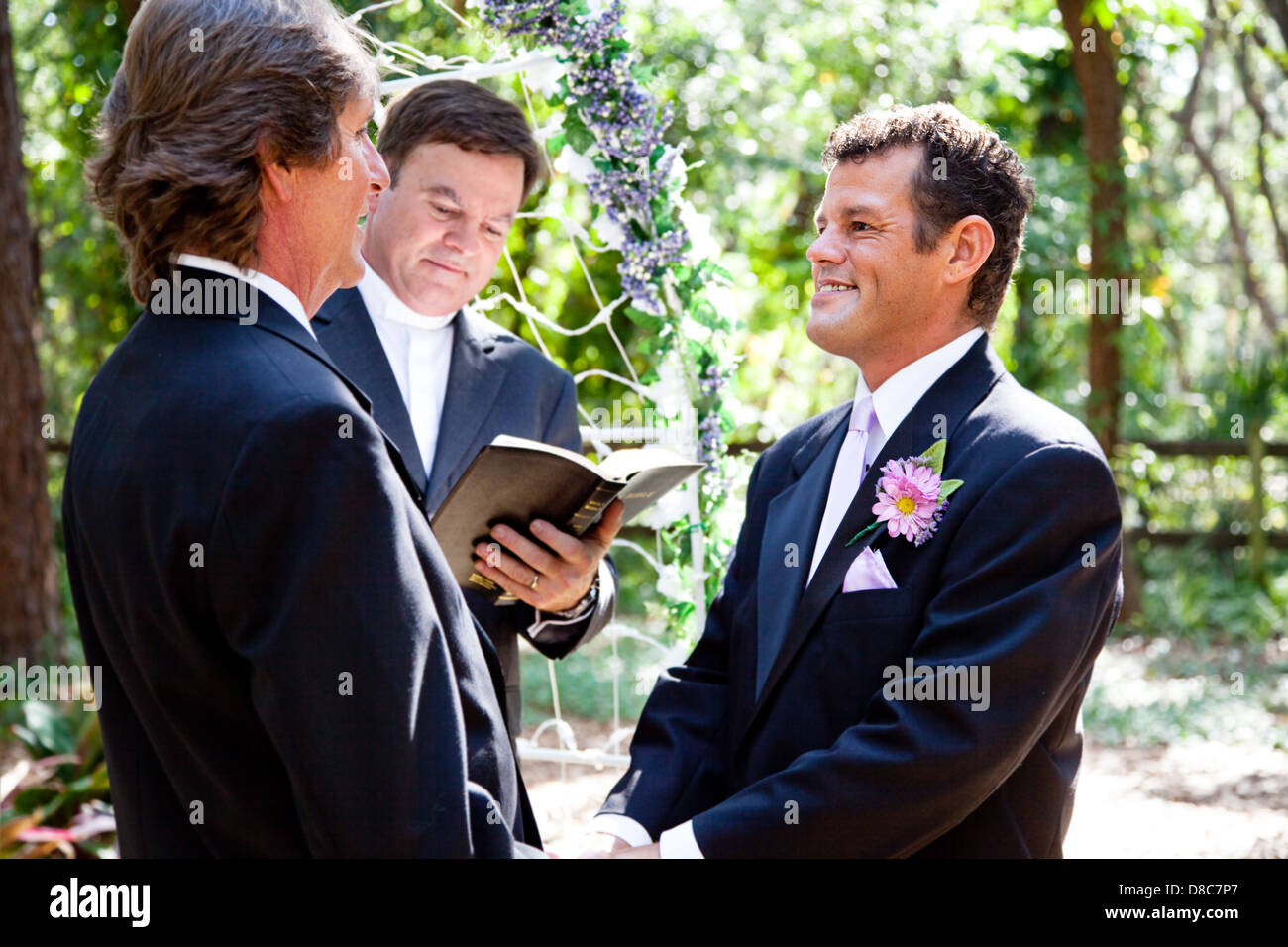Handsome gay couple getting married in beautiful outdoor ceremony.  Stock Photo