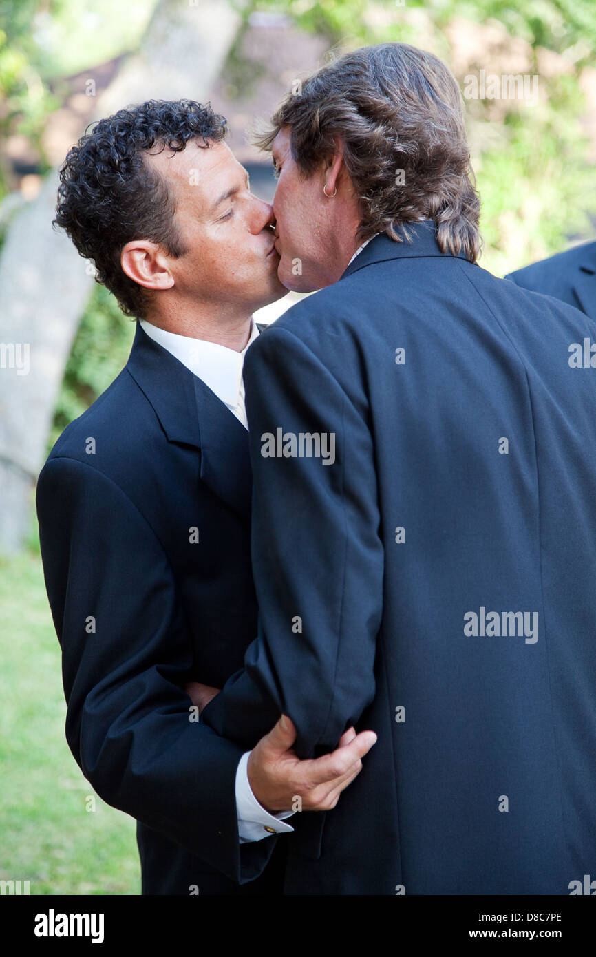 Handsome gay wedding couple, kissing at their wedding ceremony.  Stock Photo