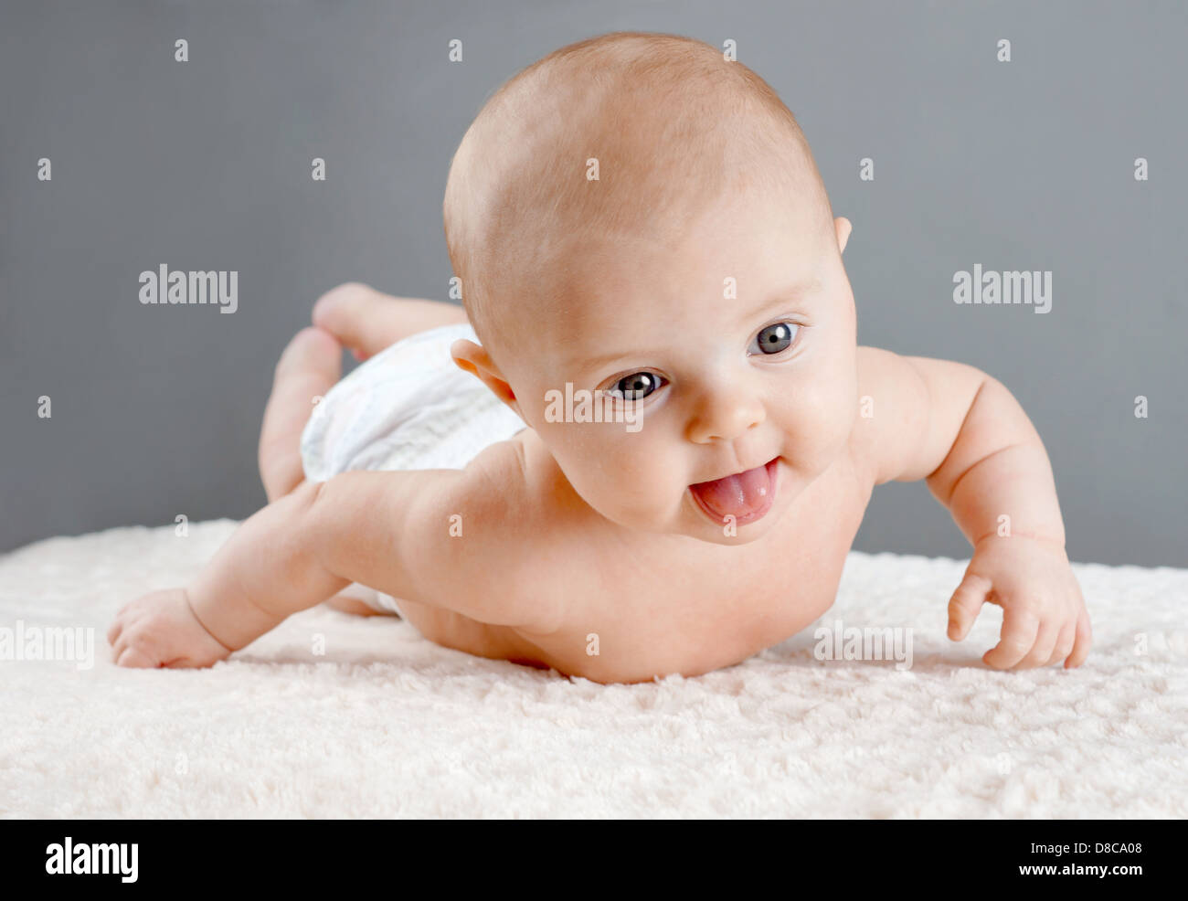 Baby on its belly, lifting its head trying to roll Stock Photo
