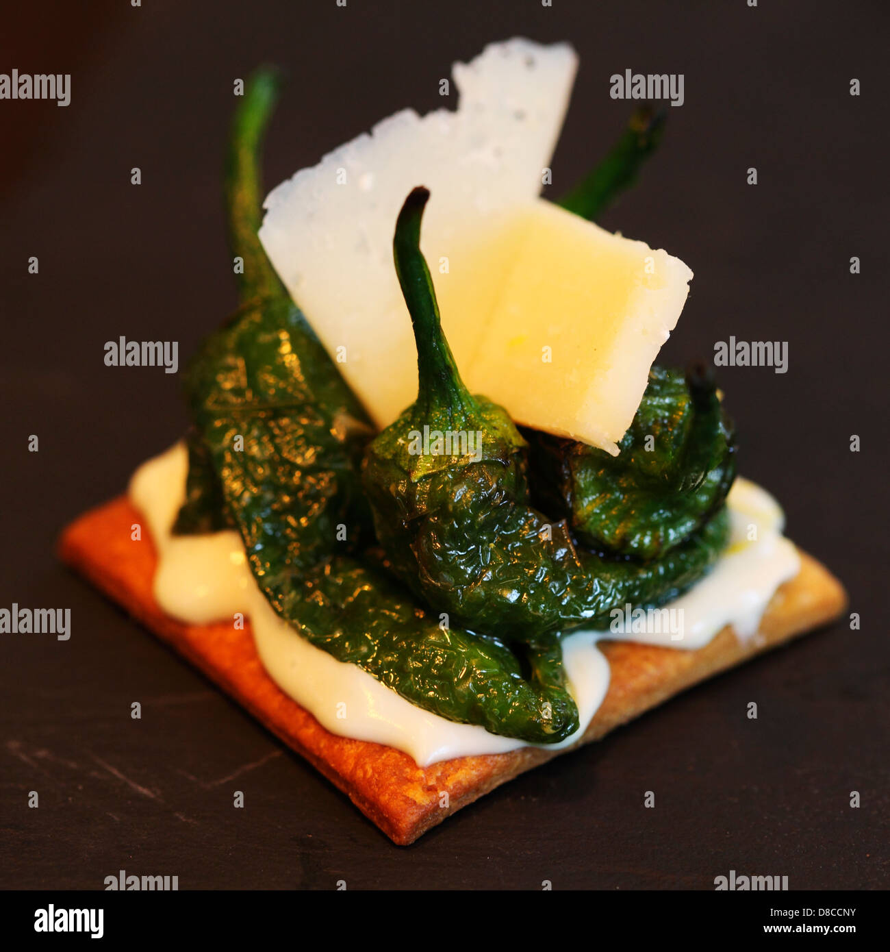A Pincho (bite sized Tapas served on freshly cooked bread) of Padron peppers, cream cheese, lemon and Parmesan cheese. Stock Photo