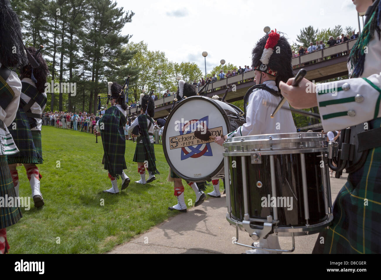 A marching band including bagpipes and drums celebrates a graduation at