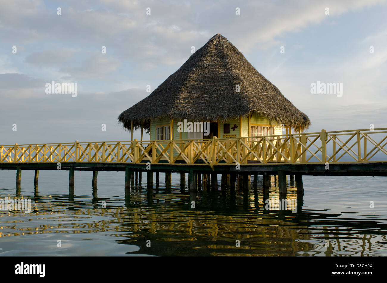 Thatch roofed bungalow on stilts in lagoon at Punta Caracol Hotel Stock Photo