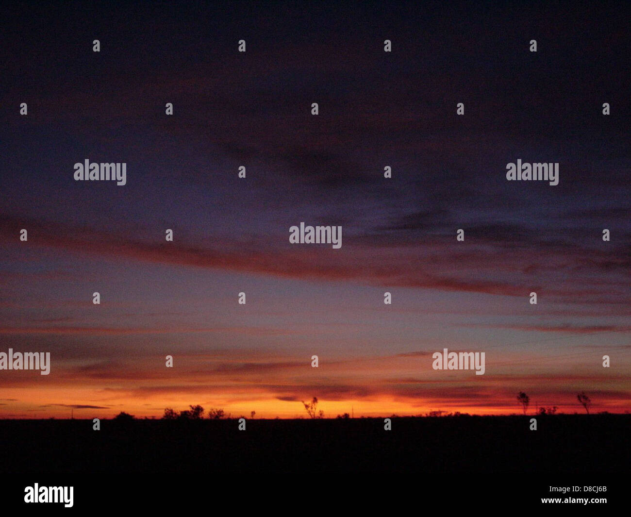 A dark sunset scene where the sun sets behind the horizon, casting rich ...
