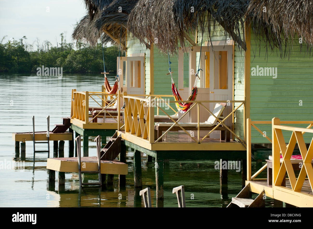 Thatch roofed bungalows on stilts in lagoon at Colon Island Stock Photo