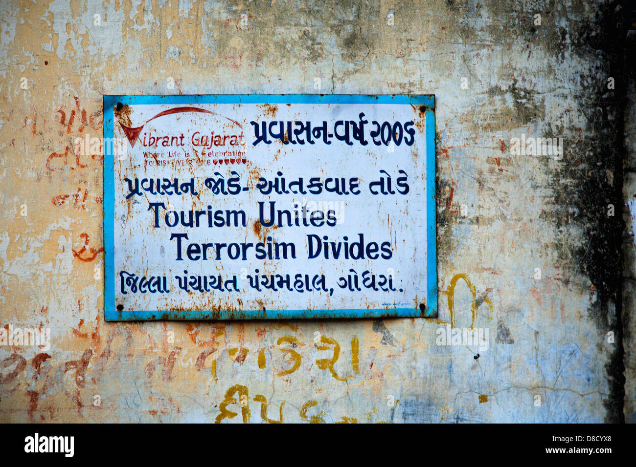 Dilapidated metal sign on a dilapidated plaster wall encouraging tourism in Gujarat, India Stock Photo