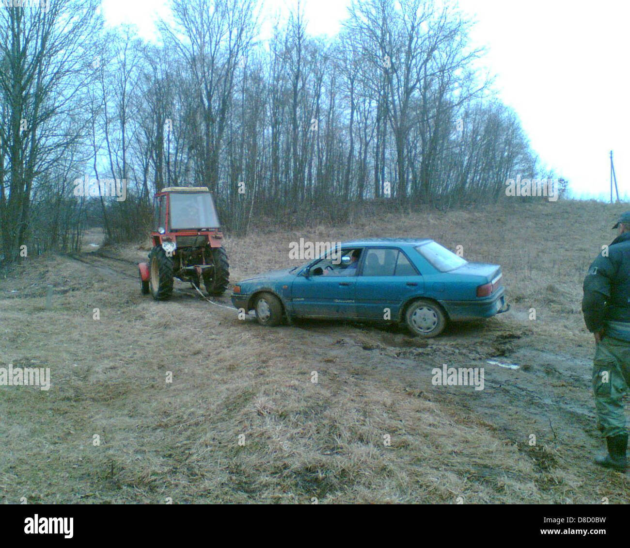 Muddy road tractor pulling car Stock Photo Alamy